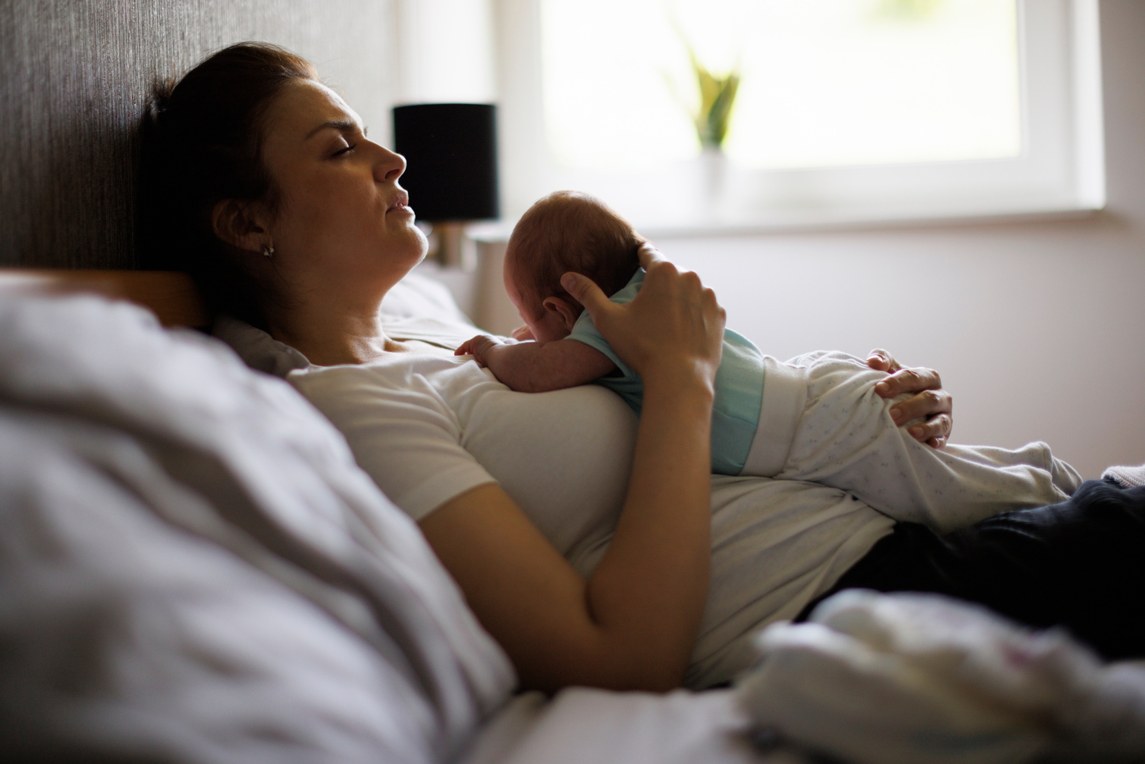 Exhausted mother holding her crying newborn baby. Postpartum depression.